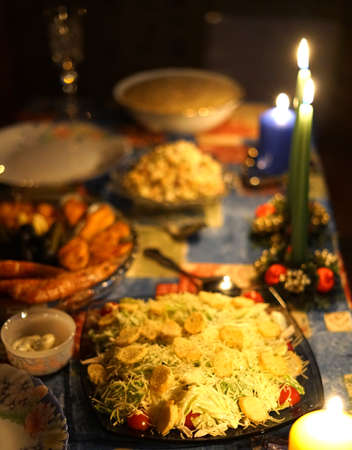 A festive New Year's table with a large number of dishes. Candles are burning and it's dark. Lifestyle.の写真素材