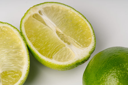One lime cut in half and one whole on a white closeup backgroundの写真素材