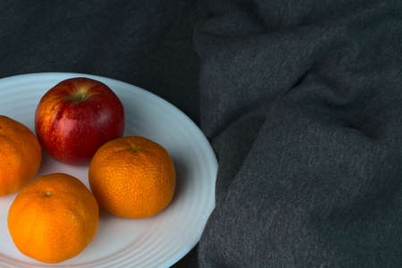 Fruit on a white plate against a background of dense crumpled fabricの写真素材