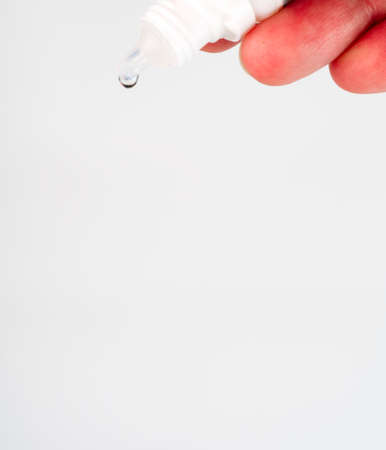 A bubble of eye drops with a hanging drop of closeup. On a white background. Space for text.の写真素材