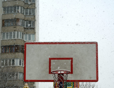 Basketball hoop with a close shield for streetball in winter. Snow is falling