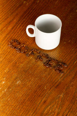 Coffee bean lettering and a white cup on a wooden background.の写真素材