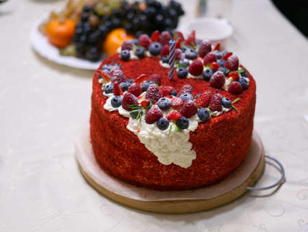 The birthday cake is on the table. Decorated with strawberries and blueberries. There is also a white cream on topの写真素材