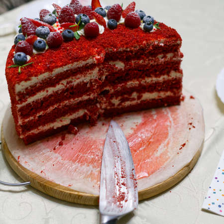 A sliced birthday cake on the closeup table. Red color with cream.の写真素材