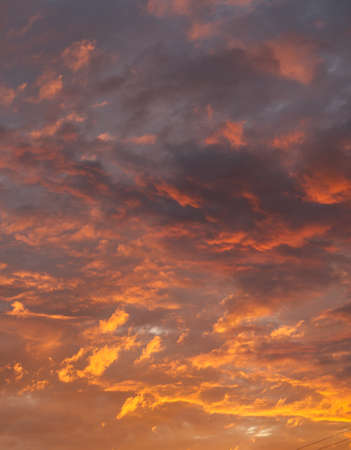 Dark orange red clouds with striking shades and a play of light. Vertical snapshotの写真素材