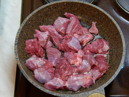 Raw pieces of red meat in a frying pan. Ready for fryingの写真素材
