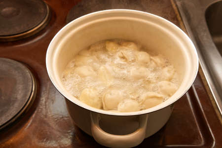 A traditional Russian dish of dumplings is cooked in a pot on an old stove. Closeの写真素材