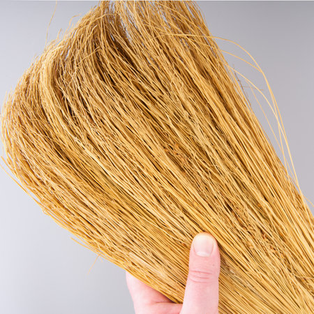 A new broom for cleaning rooms and sweeping on a light gray background in your hand. Closeの写真素材