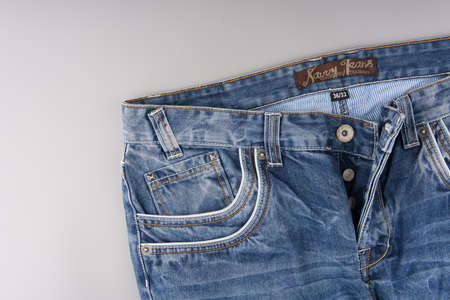 MOSCOW, RUSSIA-February 23, 2022: The front part of branded jeans with a button fly and different patterns lie on a light gray background. Place for textのeditorial素材
