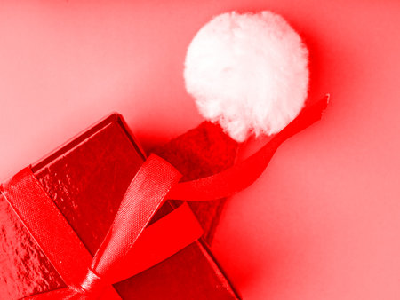 A New Years gift and a Santa Claus hat. Top view. The picture is in red tonesの写真素材