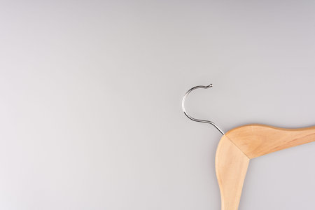 Clothes hanger on a gray background. Sticking out from behind the corner of the frame. Space for...