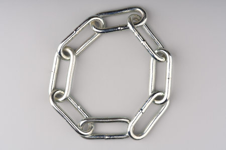 A large metal chain twisted into a circle on a gray background. Space for text