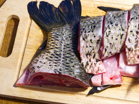 Carp cut on a cutting board in the kitchen. The tail is visibleの写真素材