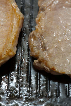 Two grilled steaks in a closeup pan. Vertical snapshotの写真素材