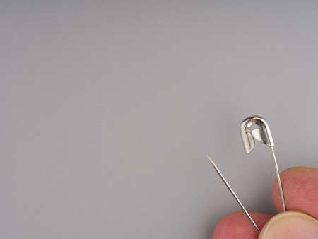 Clothing pin in hand on a gray background closeup. Space for textの写真素材