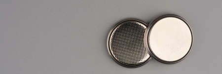Two round flat batteries on a gray background. Lots of space for textの写真素材
