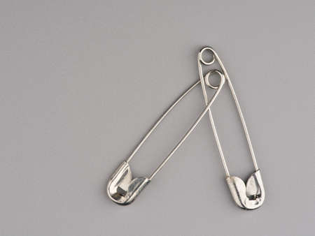 Two pins for clothes tied together on a gray background. Closeupの写真素材