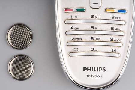 MOSCOW, RUSSIA-February 23, 2022: A TV remote control and two round batteries for it on a gray background. Closeupのeditorial素材
