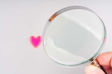 The concept of looking for love. Heart and magnifying glass in handの写真素材