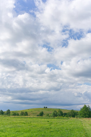 White clouds against a blue sky in summer and a green meadow. Summer.の写真素材