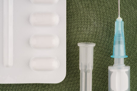 A package of pills and a syringe with an open needle is lying next to it. Closeupの写真素材