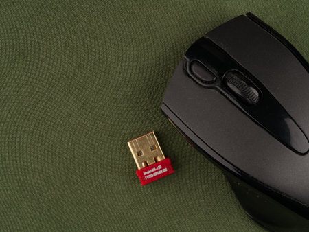 Moscow, Russia-September 16, 2022: A wireless computer mouse on a green background along with the part connected to the computer. Close up. View from aboveのeditorial素材