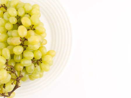 Grapes on a white plate on a white background. View from above. Space for textの写真素材