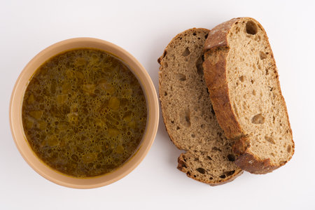 Soup in a plate and black bread on a white background. View from aboveの写真素材