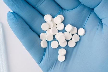 The pills lie on the hand in a blue medical glove. Closeup. View from aboveの写真素材