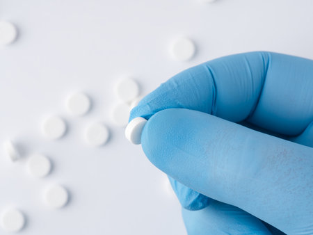 In the hand that is in a blue medical glove there is one tablet. View from aboveの写真素材