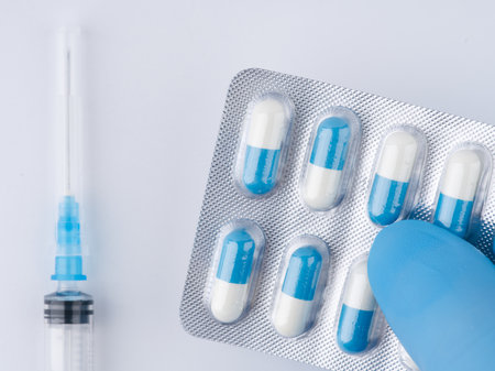 In his hand in a blue medical glove. Pills and a syringe are lying next to him. closeup.の写真素材
