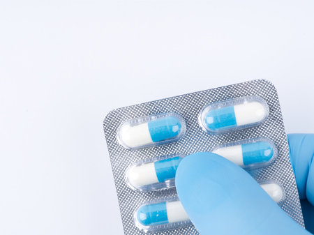 In his hand in a blue medical glove pills. Closeupの写真素材