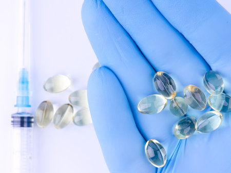 The pills lie on the hand in a blue medical glove and syringe. Closeup. View from aboveの写真素材