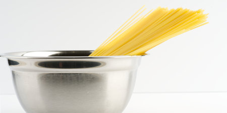 Pasta in a metal bowl on a white background. Side viewの写真素材