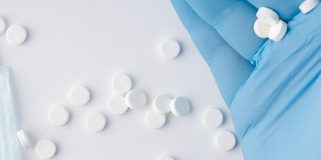 In the hand that is in a blue medical glove there is tablets. View from aboveの写真素材