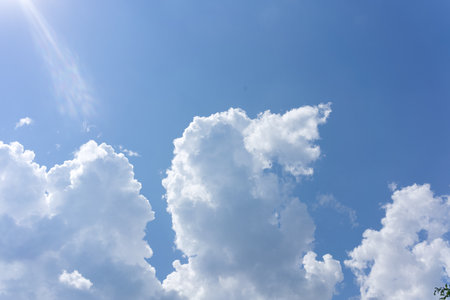 White clouds on a blue sky in summer. And the sun looks out.の写真素材