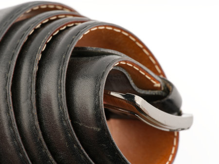 Black leather belt on a white background twisted. Closeup. Place for textの写真素材