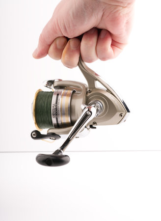 Moscow, Russia-October 16, 2022: Fishing reel on a white background in hand. Place for textのeditorial素材