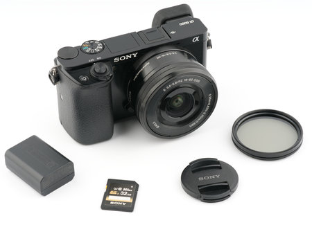 Moscow, Russia-October 16, 2022: The old Sony A6000 mirrorless camera is black on a white background. Nearby are a memory card with a battery and an ND filterのeditorial素材