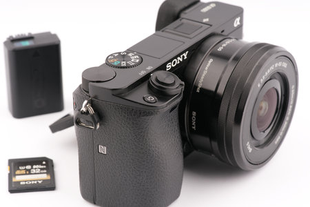 Moscow, Russia-October 16, 2022: An old Sony A6000 mirrorless camera in black with a battery and a memory card on a white backgroundのeditorial素材