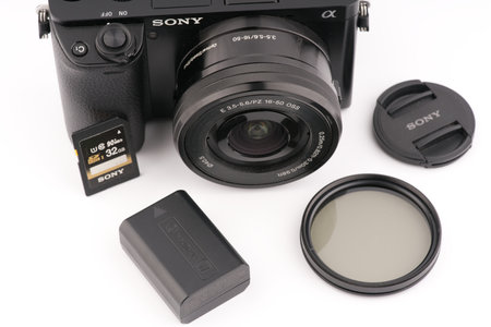 Moscow, Russia-October 16, 2022: The old Sony A6000 mirrorless camera is black on a white background. Nearby are a memory card with a battery and an ND filter. View from aboveのeditorial素材