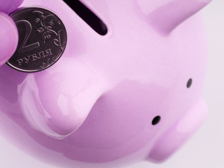 They put a coin in the piggy bank in pink. Closeup. Space for textの写真素材
