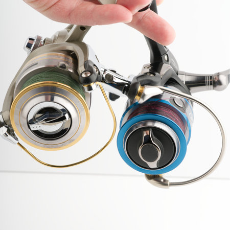 Moscow, Russia-October 16, 2022: Two different branded fishing reels in hand on a white backgroundのeditorial素材
