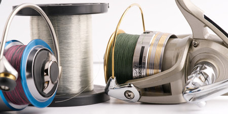 Moscow, Russia-October 16, 2022: Two different branded fishing reels and a large skein of fishing line on a white backgroundのeditorial素材