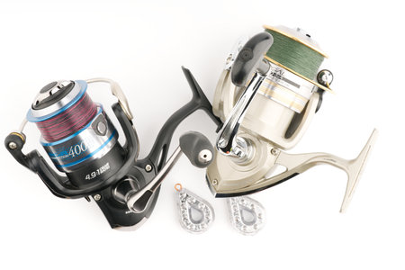 Moscow, Russia-October 16, 2022: Two branded fishing reels and weights on a white background. Flatlayのeditorial素材