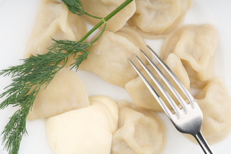 Cooked dumplings on a white plate with dill and fork. Flatlayの写真素材