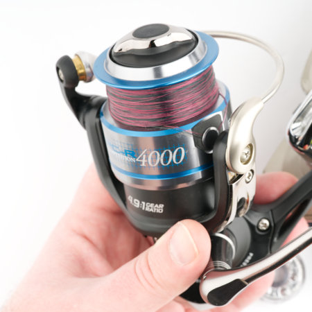 Moscow, Russia-October 16, 2022: Branded fishing reel in a hand on a white background. Closeupのeditorial素材