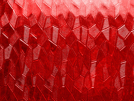A complex abstract texture made of glass with randomly arranged rhombuses of red color. Closeup