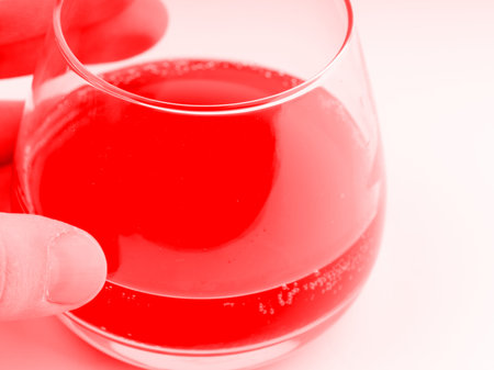In the hand of an octel in a glass in red colors. Closeupの写真素材