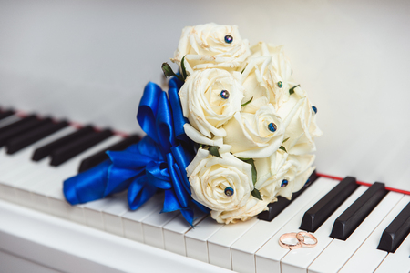 a bouquet and a ring lying on a white piano. Beautiful vintage wedding backgroundの写真素材